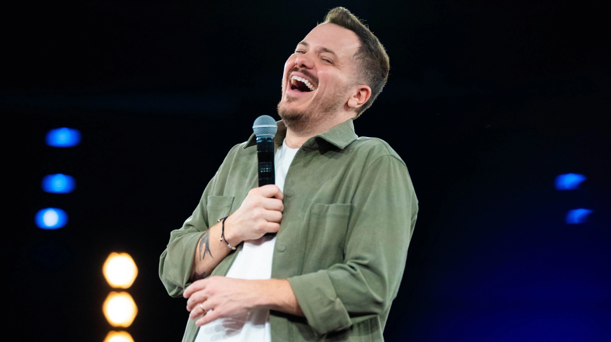Jeff Arcuri laughing with a microphone during a live stand-up show